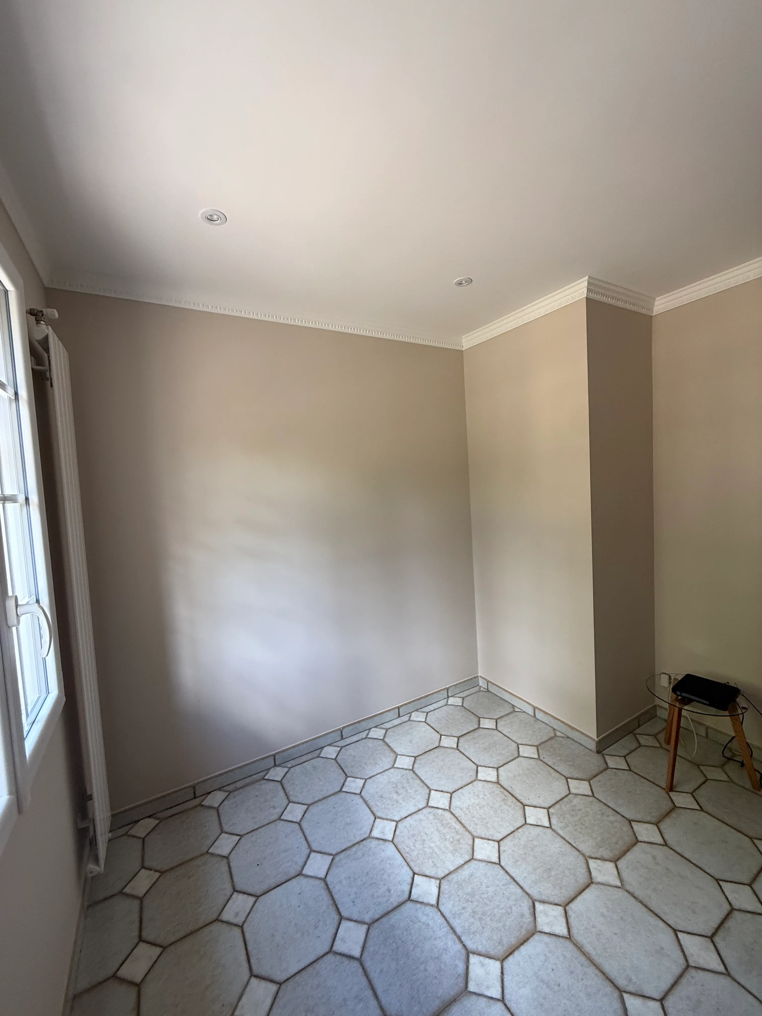 Pièce renovée avec murs en finition beige-greige mate, corniches et moulures en staff au plafond, carrelage octogonal ancien — peinture intérieure LK Peinture