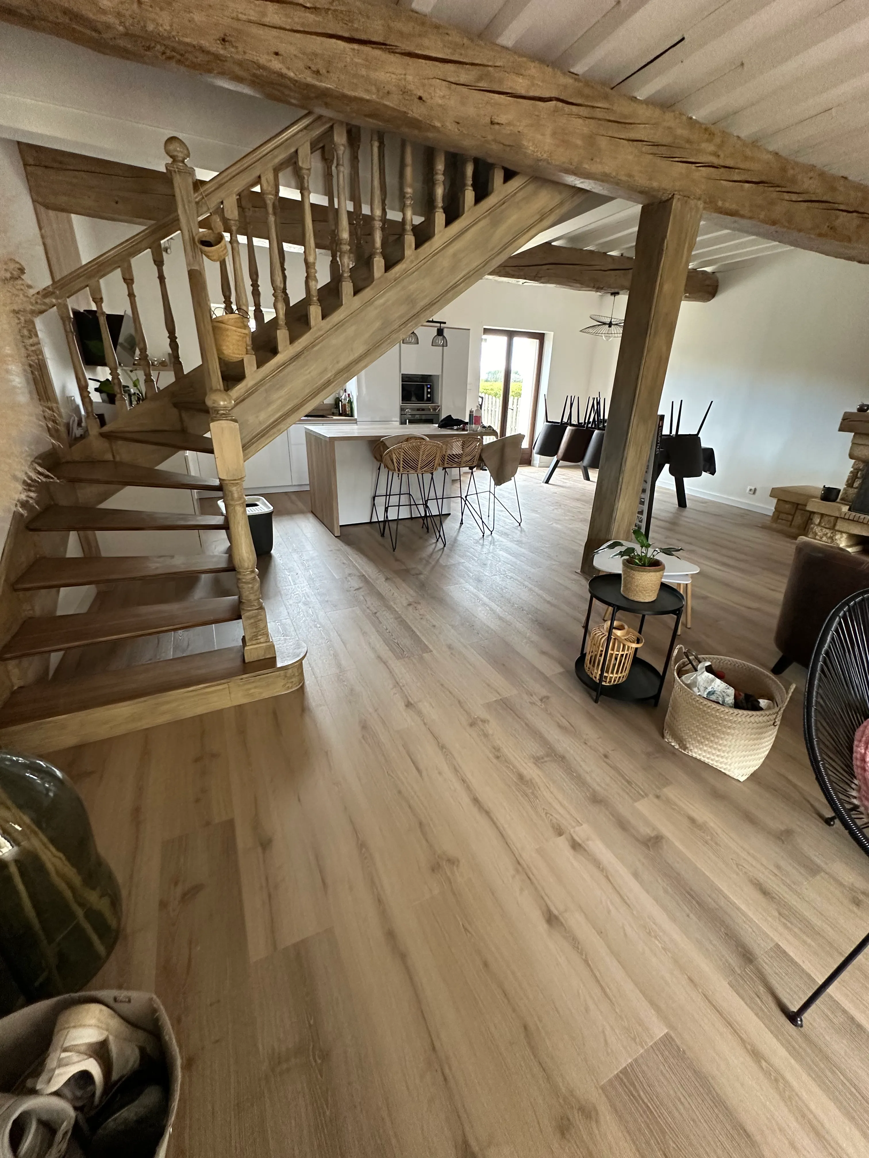 Parquet clair posé dans une grande pièce de vie avec poutres en bois apparentes et escalier traditionnel — réalisation LK Peinture dans le secteur de Carcassonne
