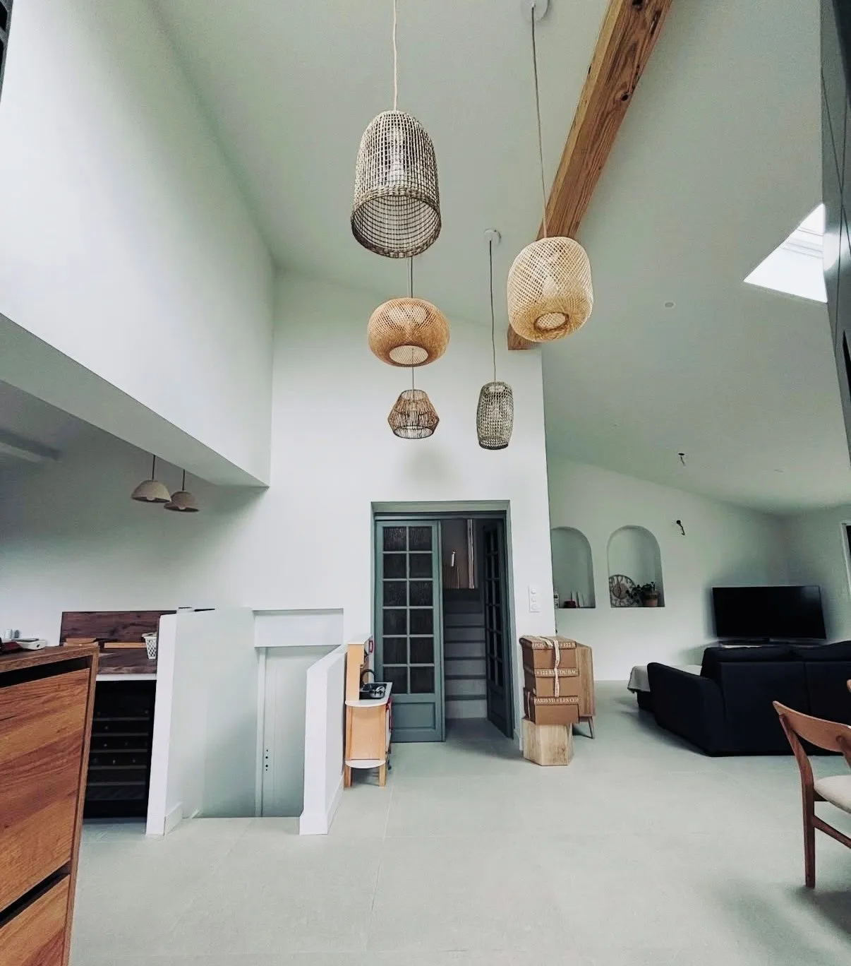 Grand séjour rénové à hauts plafonds avec poutres apparentes et murs lissés — type de logement courant dans les rénovations carcassonnaises