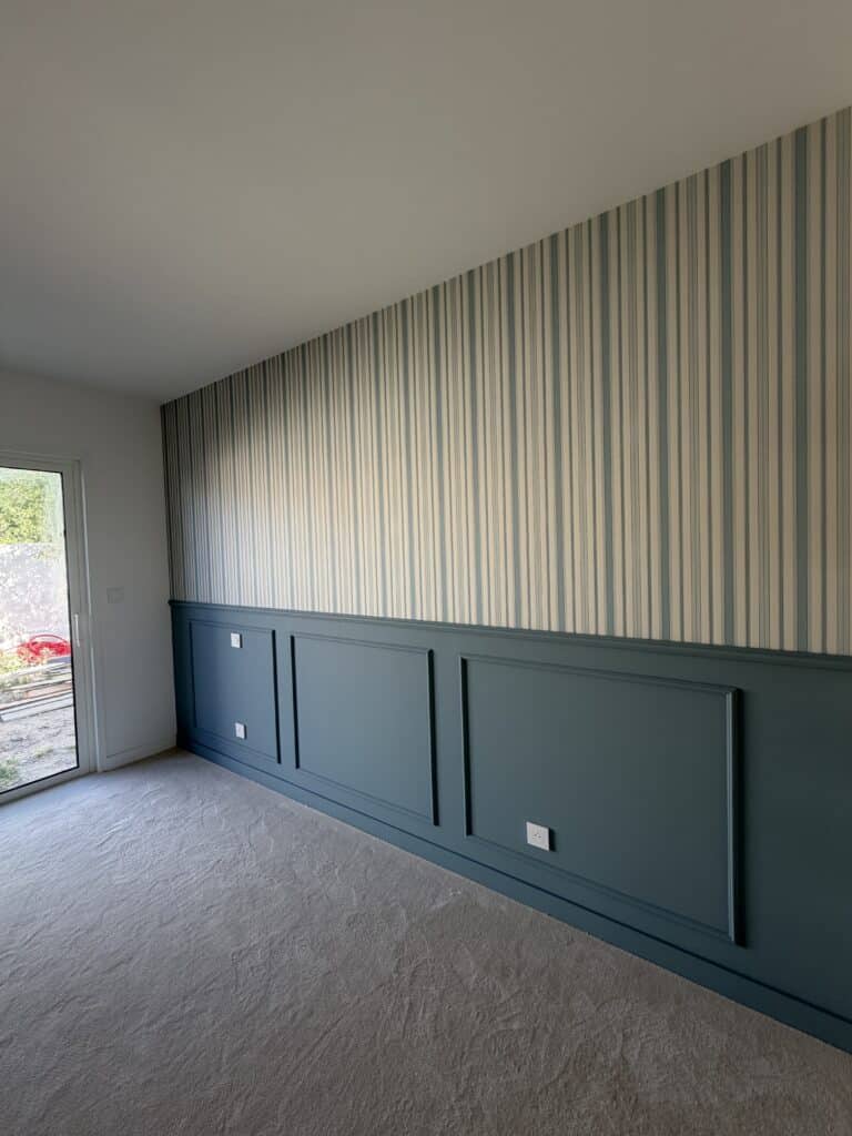 Déco Murale : Papier Peint Rayé et Soubassement Bleu Mur avec papier peint rayé bleu et soubassement à moulures bleu canard sur moquette grise.